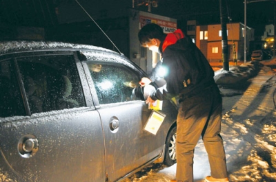 写真：違法駐車車両に注意文書を取り付ける市職員