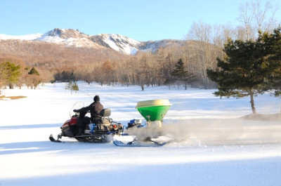 写真：スノーモービルでコース内に融雪剤をまくスタッフ＝２５日午前７時５０分ごろ、伊達市北有珠町