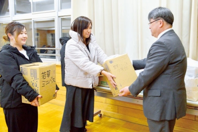 写真：大熊校長（右）に雑巾を手渡す同後援会メンバー