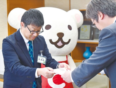 写真：堀井市長に目録を手渡すコープさっぽろの豊田宅配事業本部長