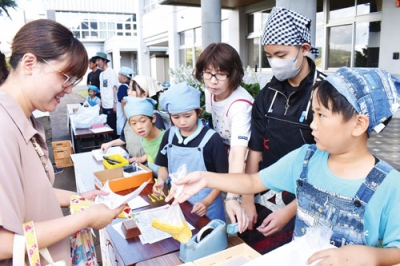 写真:丹精したトウモロコシを客に販売する関内小の児童ら