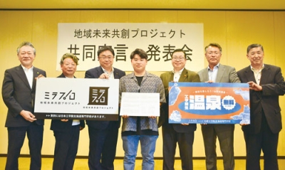 写真:温泉無料やロゴマークのプラカードを持つ6団体の代表と学生代表の土居さん(中央)