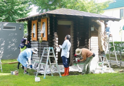 写真:ログハウス風物置のペンキを塗り直す参加者(提供写真)