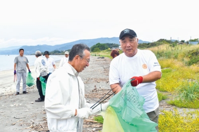 写真:砂浜に落ちたごみを火ばさみで拾う伊達RCの会員たち