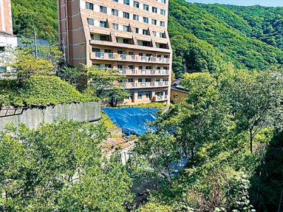 写真:大雨の影響で温泉ホテル社員寮裏のコンクリート舗装部分が崩落した