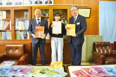 写真:川上参事(右)から百科事典を手渡された下國さんと猪子校長