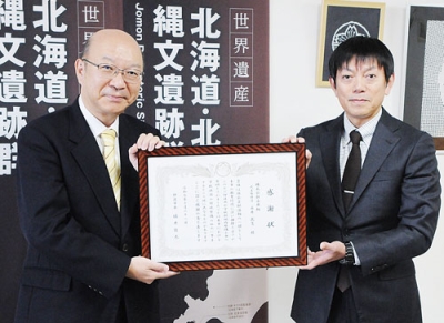 写真:感謝状を手にする永井代表取締役(右)