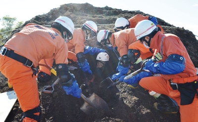 写真:災害救助の訓練で、土砂に埋まった人を救出するため慎重に掘削を進める隊員たち