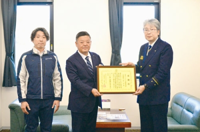 写真:沼田消防長(右)から感謝状を受け取った中谷代表取締役(中央)ら