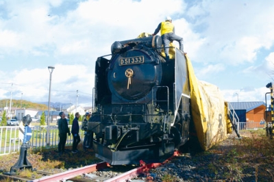 写真:冬囲いでシートがかけられる蒸気機関車