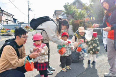 写真:職員からシールをもらい笑顔を見せる仮装した親子ら