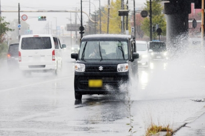 写真:雨で水たまりができた道路を、水しぶきを上げながら走行する車=1日午後0時40分ごろ、室蘭市輪西町