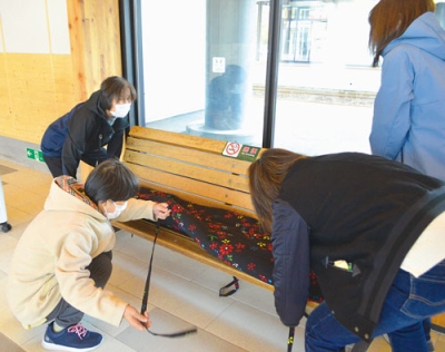 写真:ベンチに座布団を敷く会員たち