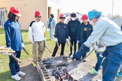 写真:まきを手にオリジナル縄文土器の焼き上がりを待つ虻田小児童ら