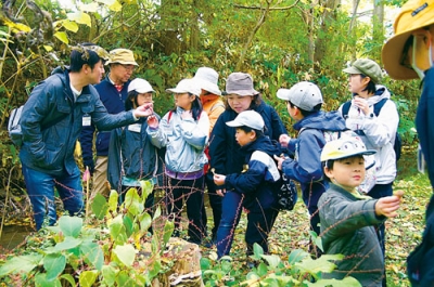写真:興味深くキノコを観察する参加者(提供写真)