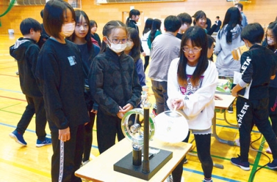 写真:うちわで風車を動かし、電気を起こす実験に臨む児童ら