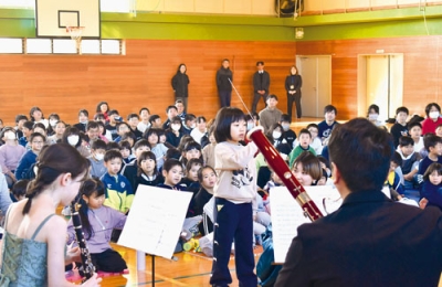 写真:タクトを振って指揮者気分を味わう児童