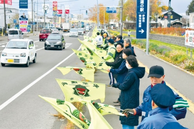 写真:寒風の中「旗の波」をつくり、ドライバーに安全運転を促す参加者
