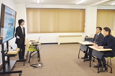 写真:望月代表取締役(右から2人目)らに業務改善案をプレゼンする赤坂さん