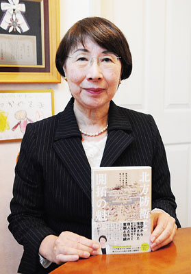 写真:著書「北方防衛と開拓の魁」を手に笑顔を見せる中村さん