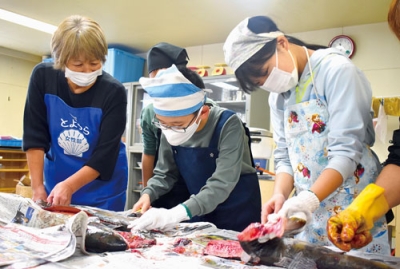 写真:真剣なまなざしでサケに包丁を入れる児童