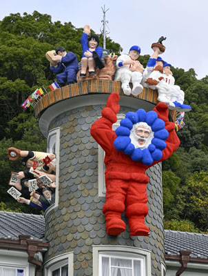 写真:大阪・関西万博のキャラクター「ミャクミャク」を思わせるコスチュームで登場した「世相サンタ」=19日午前、神戸・北野の異人館「うろこの家」