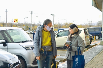 写真:買い物客に啓発物を渡す市職員