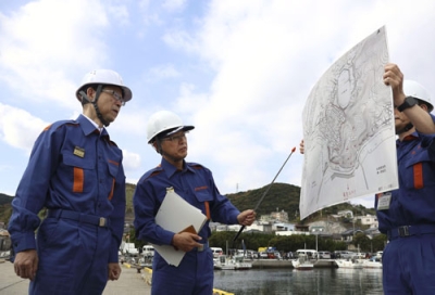 写真:大分市佐賀関の火災現場を訪れ、被災状況の説明を受ける大分県の佐藤樹一郎知事(左)=20日午前11時2分