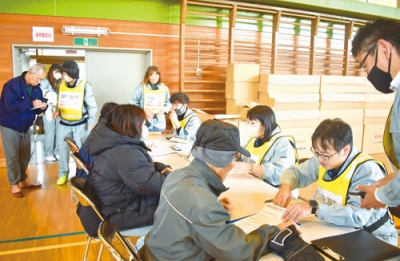 写真:避難者カードに必要事項を記入する訓練参加者ら=虻田小学校