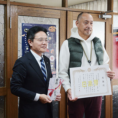 写真:町に現金100万円を寄付した髙田代表取締役(右)と大塩町長