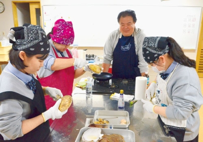 写真:ホタテの貝殻をむく方法を教わり、調理する生徒