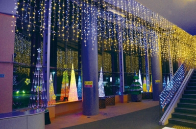 写真:天井からつり下げられたLEDの光を反射させるホワイエの窓ガラス