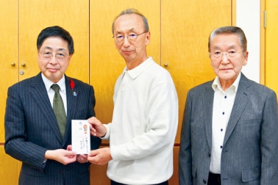 写真:髙木事務局長(左)に善意を手渡す柴原さん(中央)、小林さん