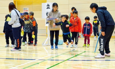 写真:体力テストで立ち幅跳びに挑む子どもたち