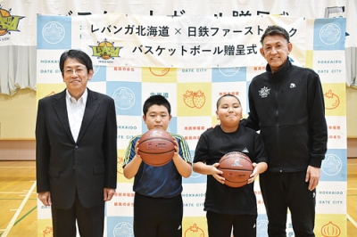 写真:関内小で児童にボールを贈った折茂社長(右端)と篠原社長(左端)