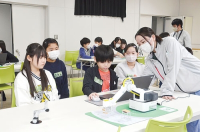 写真:プログラミングしたロボットのアームを動かす児童ら