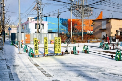 写真:陥没事故から1カ月がたった東町の市道。陥没地点はフェンスで保護され、手前の交差点は通行止めが続いている=4日