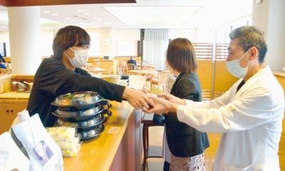 写真:ランチタイムにマルクマの弁当を購入する病院関係者(右)