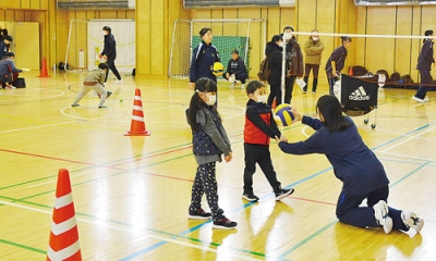 写真:地域クラブの中学生からバレーボールを教わる子どもたち