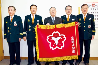 写真:沼田会長(中央)から市消防団に寄贈された新しい団旗