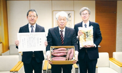 写真:組合員が丹精し育てたサツマイモを手にする佐藤組合長(中央)