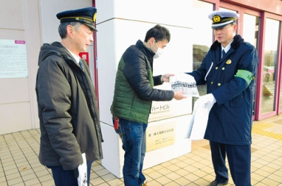 写真:来店客に特殊詐欺被害防止の啓発品を手渡す渡部署長(右)