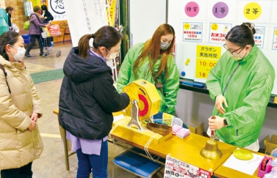 写真:ガラポン抽選に挑む買い物客ら