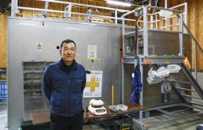 写真:「減容化装置」の前に立つ、BOD商会代表の高原正樹さん=11月、福島町