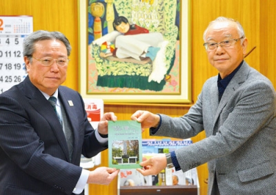 写真:安宅教育長(左)に本を手渡す小坂さん