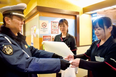 写真:店員に啓発物を配り、飲酒運転根絶への協力を求める渡部署長(左)