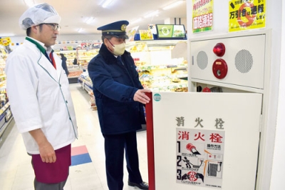 写真:店内の防火設備を目視で確認する消防職員(右)