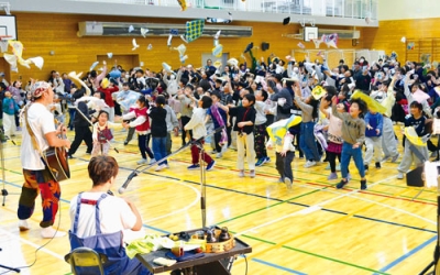 写真:「ひのき屋」の演奏に合わせ、ハンカチを投げて盛り上がる児童たち