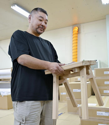 写真:商品のいすを手にする「石巻工房」の千葉隆博さん=2025年10月、宮城県石巻市