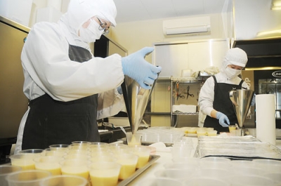 写真:手作業でプリンを容器に詰める従業員